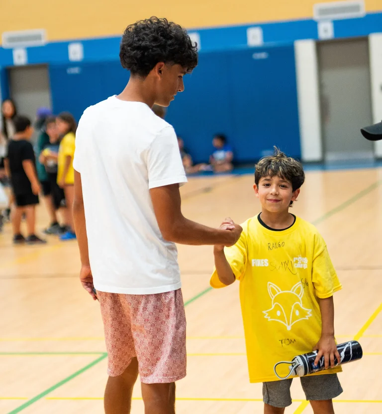 A camper and a staff member shake hands during a moment at Rouge Camps.
