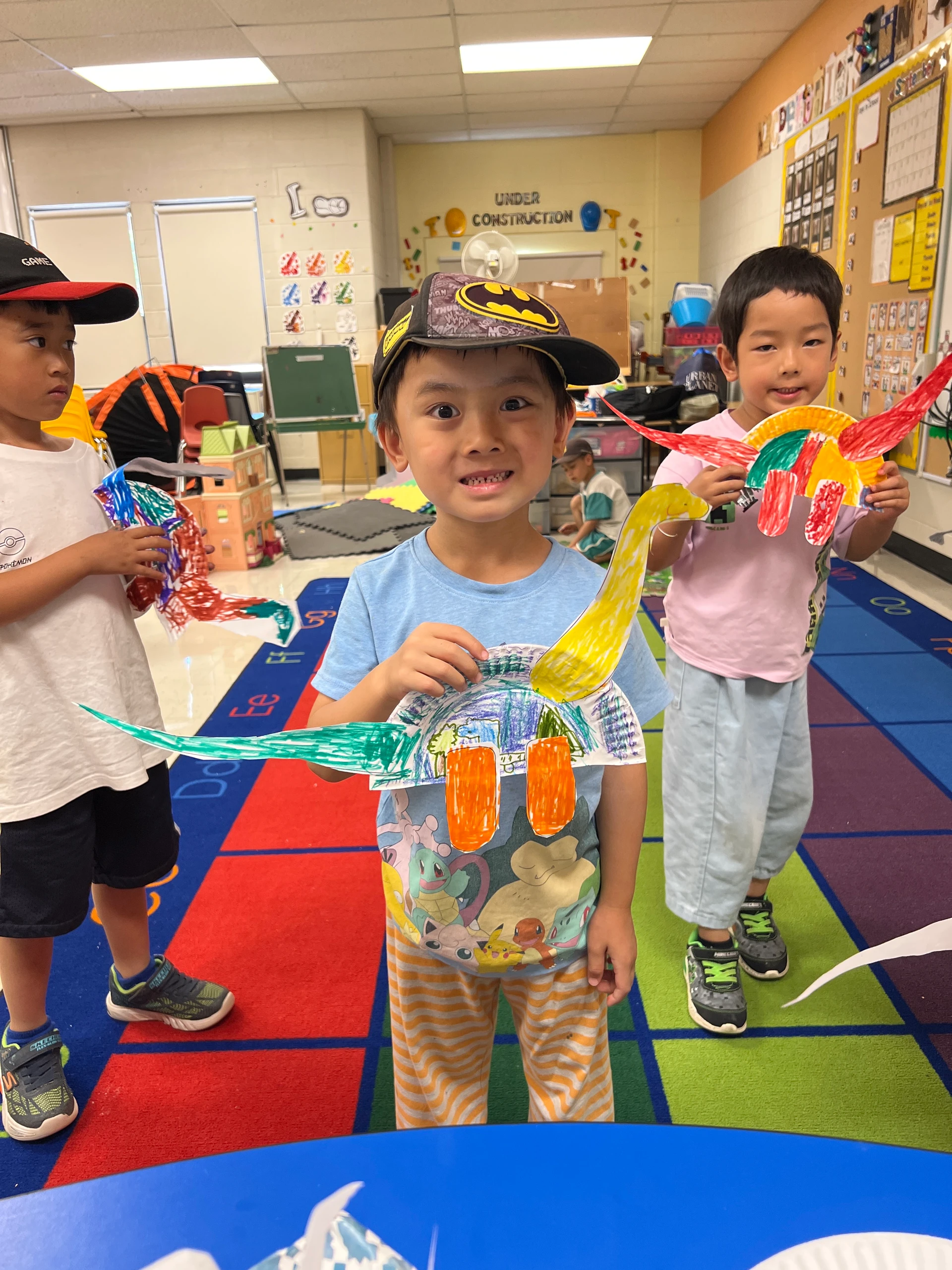 A deer camper proudly shows his arts and crafts creation to the camera with friends looking on at Rouge Camps.