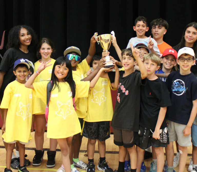 A group of campers raising a trophy after winning a tournament at Rouge Camps Richmond Hill.