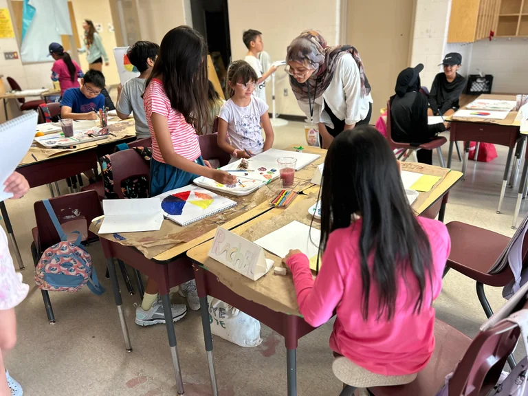 An Art Camp expert instructor reviews a camper art piece and gives supportive feedback at Rouge Camps Unionville.