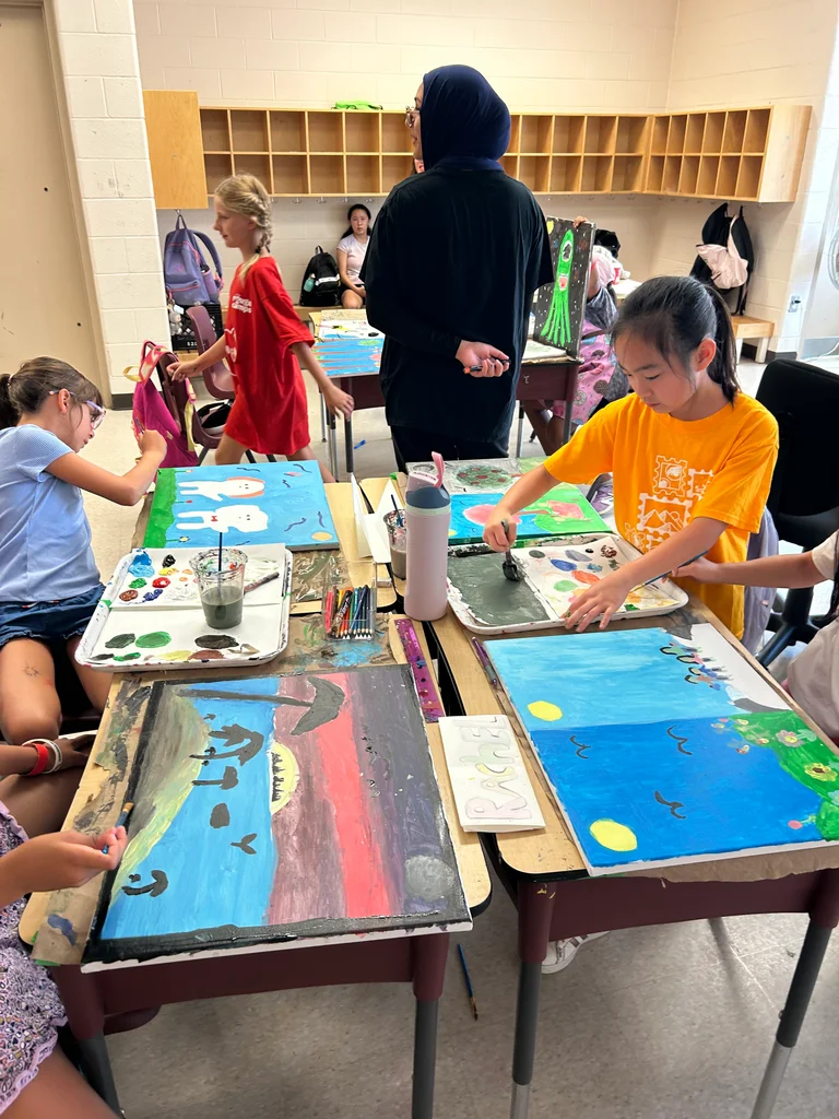 A camper carefully adds to her canvas during an Art Camp session at Rouge Camps Woodbridge.