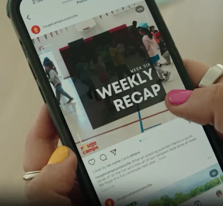 A mom checking her phone for Instagram updates while their child is attending Rouge Camps. Image showing painted finger nails and an Instagram post on their mobile phone.