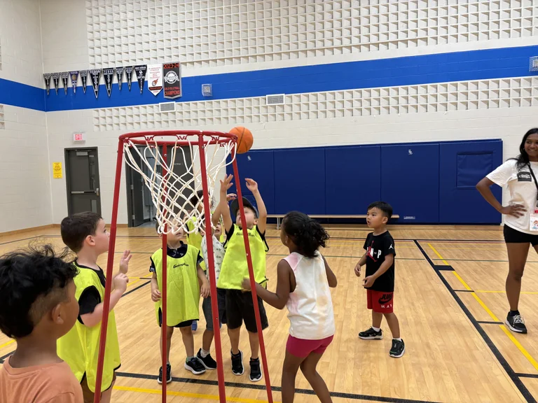 A group of rabbit campers in bright pinnies play basketball on a modified net so that they can experience success and build confidence at Rouge Camps Woodbridge.
