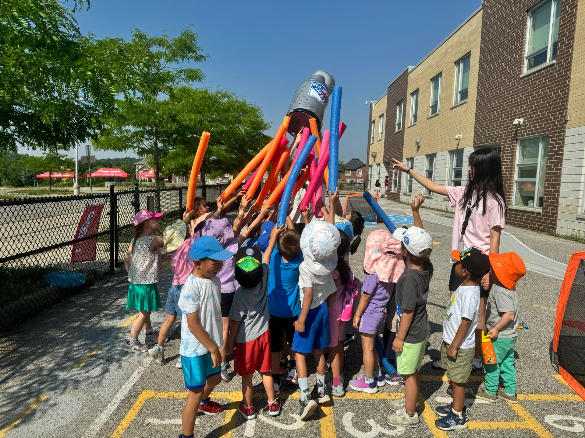 A group of rabbit campers reaching as high as they can in the air towards an inverted bucked having fun in this colourful photo at Rouge Camps.