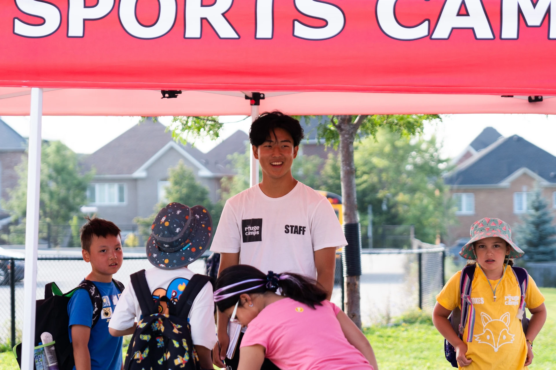 A staff member smiles while greeting campers at Rouge Camps Woodbridge.