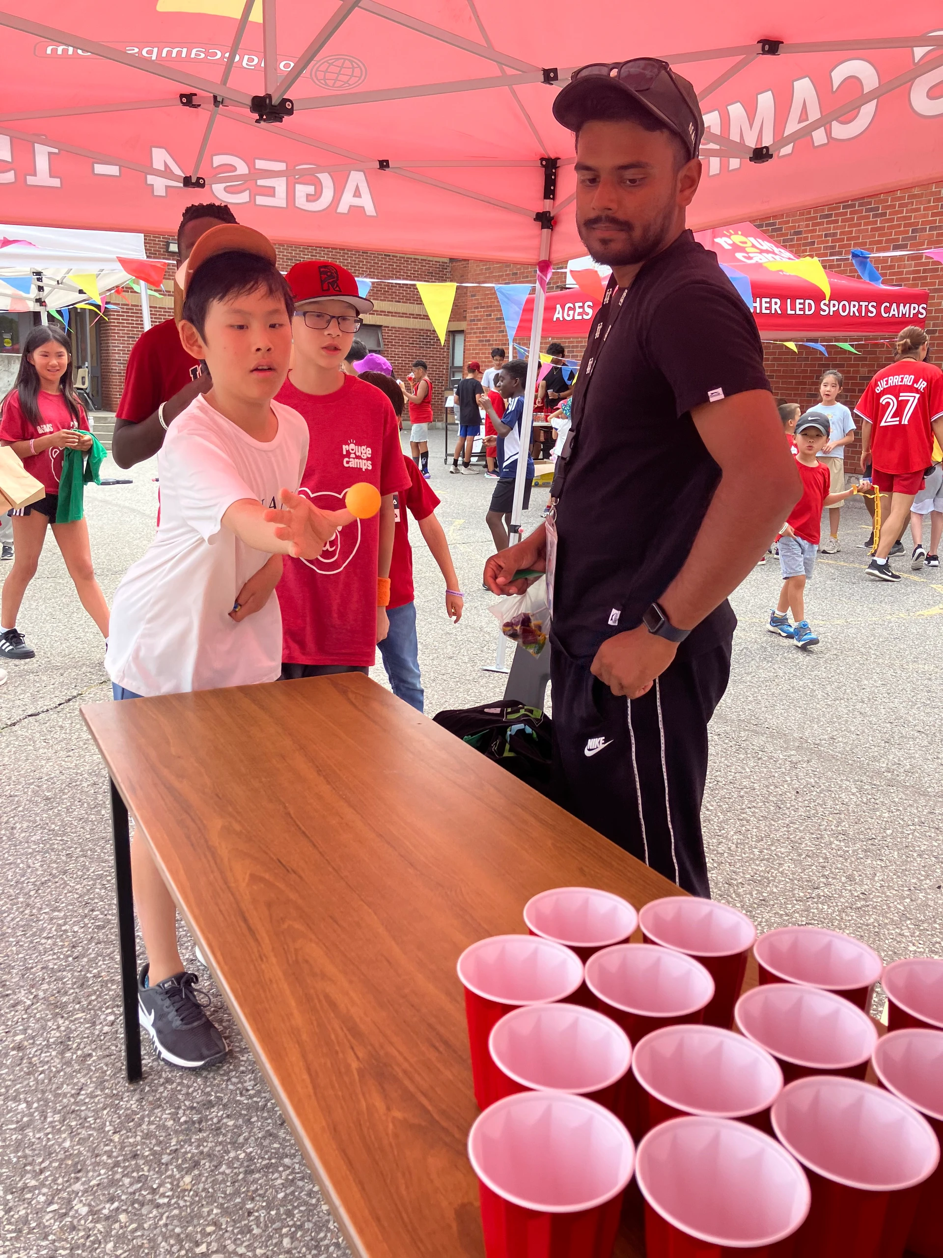 A staff member watches on as a camper plays a carnival game at Rouge Camps Unionville.