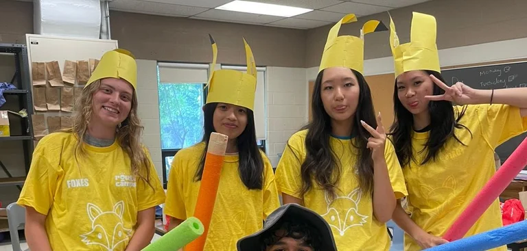 A group of staff and volunteers smile all in pokemon costumes to entertain campers.
